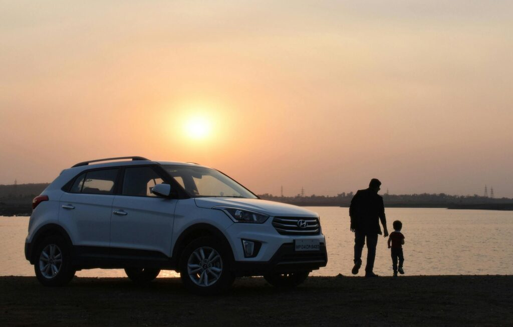 A touching silhouette of a father and son beside a car at sunset by a lake in Bhopal, India.